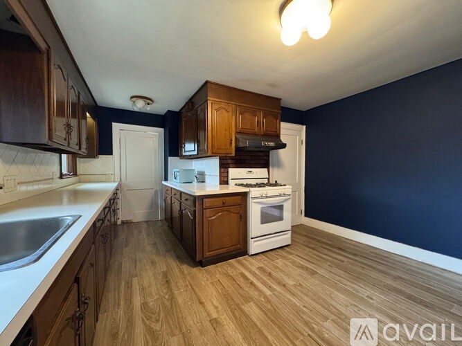 A kitchen with wooden cabinets and a white stove top oven.