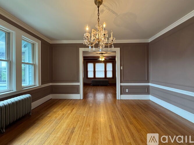 A large room with wooden floors and a chandelier hanging from the ceiling.