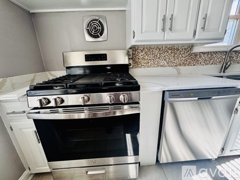 A modern kitchen with a stainless steel stove and white cabinets.