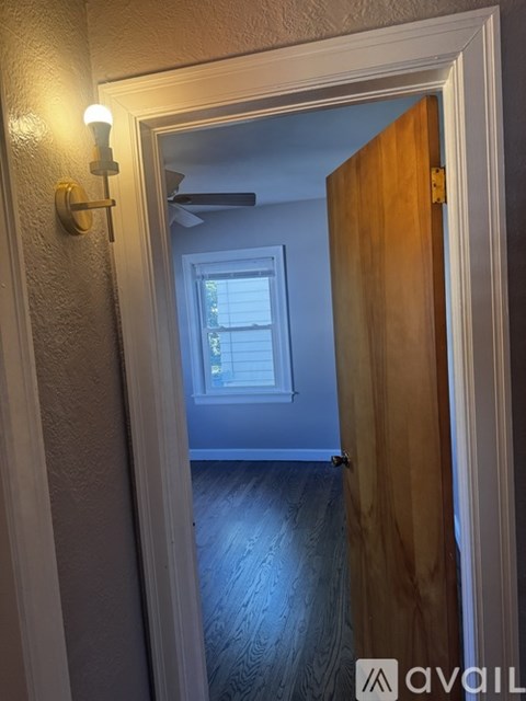 A hallway with a wooden door and a light on the wall.