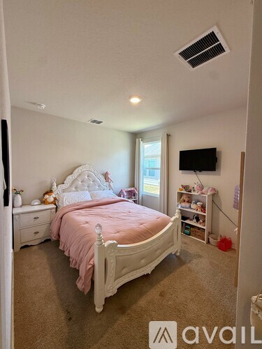 A bedroom with a pink bedspread and a white bed.
