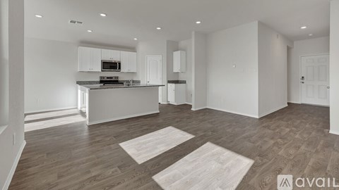 A spacious kitchen with white cabinets and a wooden floor.