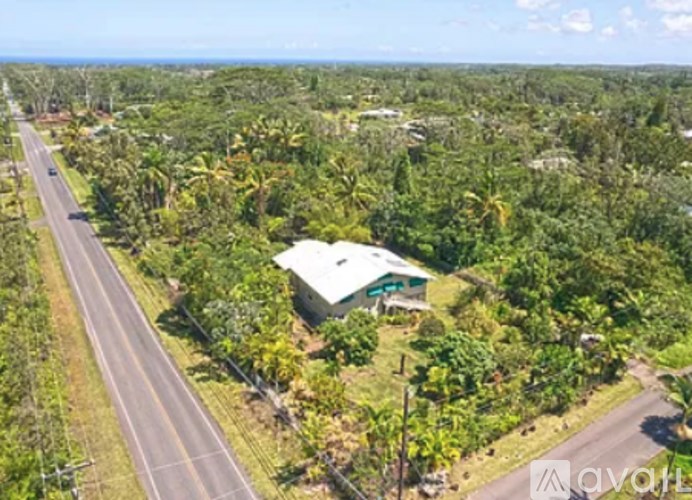 A house surrounded by greenery with a road passing by.