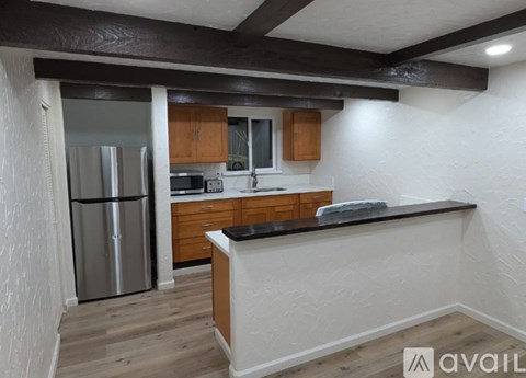 A kitchen with wooden cabinets and a stainless steel refrigerator.
