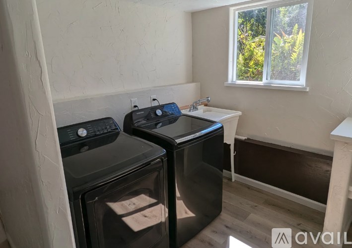 A small room with a black fridge, a black microwave, and a white sink.