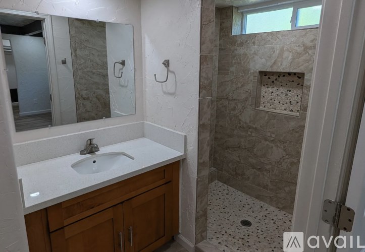 A bathroom with a sink, mirror, and shower.