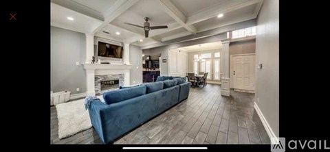 A spacious living room with a blue couch and a fireplace.