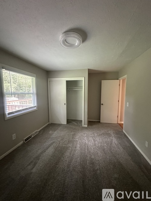 A room with a carpeted floor and a window with blinds.