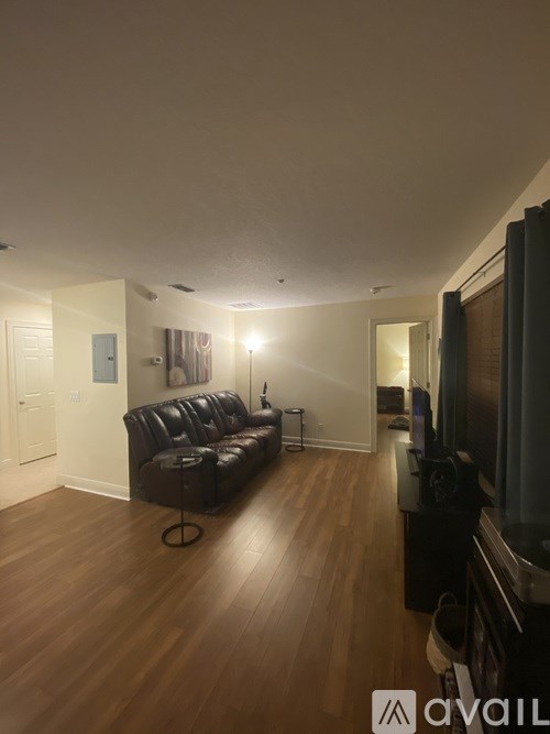 A living room with a black leather couch and a television.