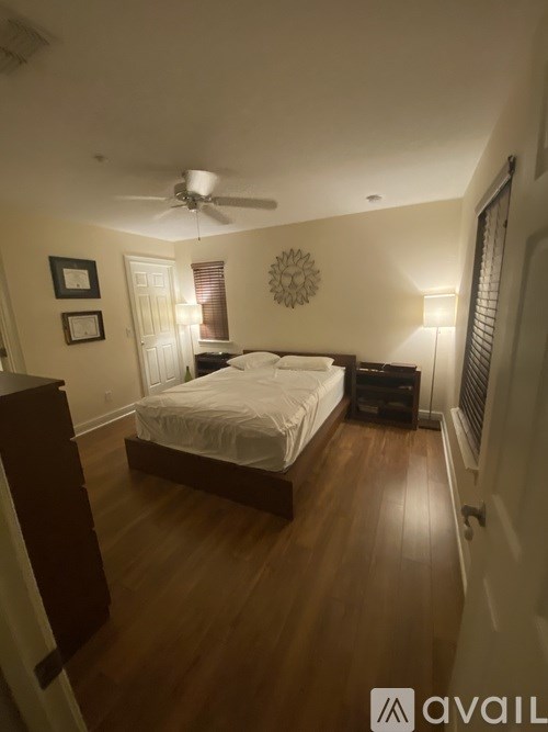 A bedroom with a bed, dresser, and ceiling fan.