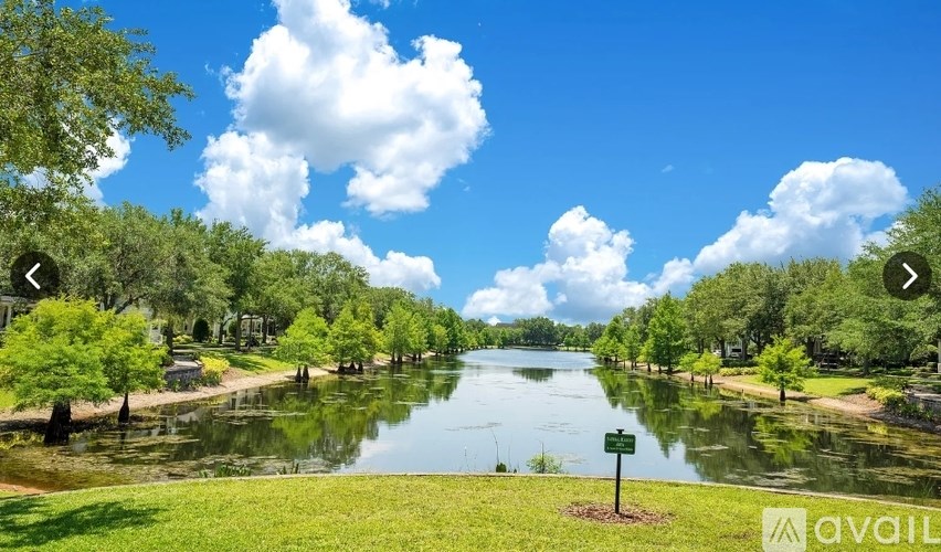 A serene lake surrounded by lush greenery under a clear blue sky.