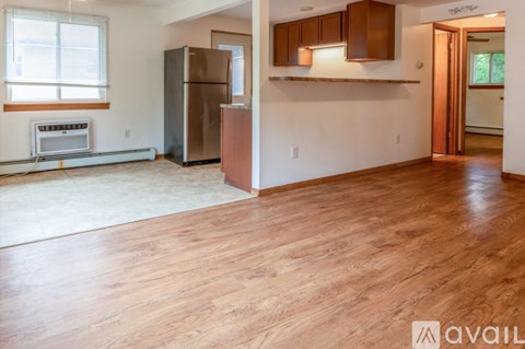 A kitchen area with a refrigerator and wooden flooring.