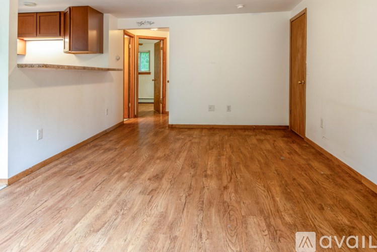 A room with wooden flooring and a door leading to another room.