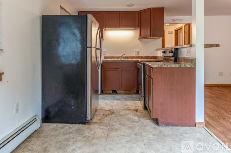 A kitchen with a black refrigerator and brown cabinets.