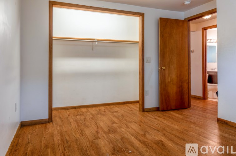 A room with a wooden floor and a door leading to another room.
