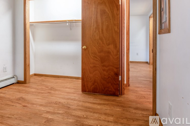 A room with a wooden door and a white wall.