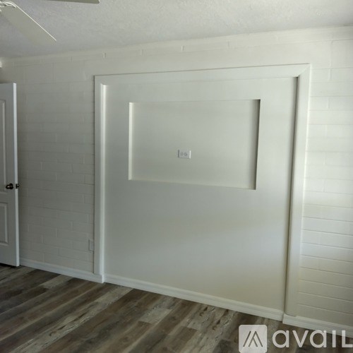 A white door with a glass window is in a room with wooden flooring.