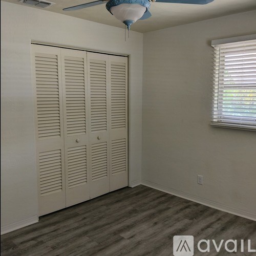 A room with a ceiling fan and a window with blinds.