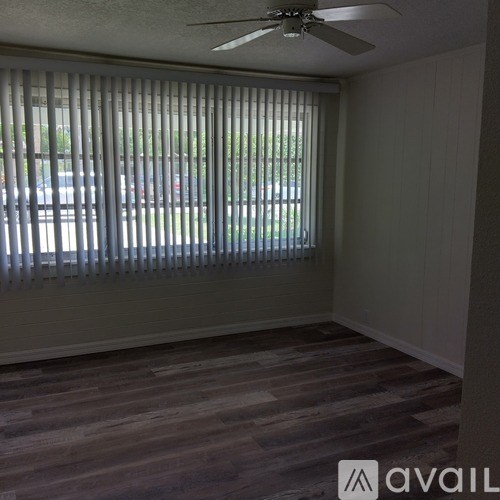 A room with a fan and a window covered with blinds.