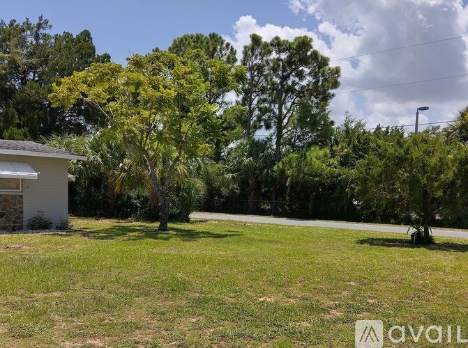 A grassy area with trees and a house in the background.