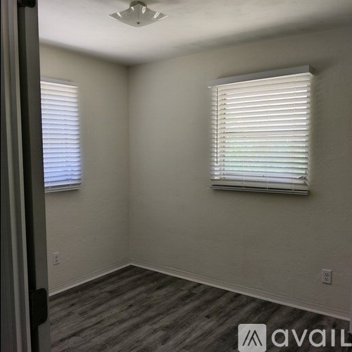 A room with a window covered by white blinds and a wooden floor.