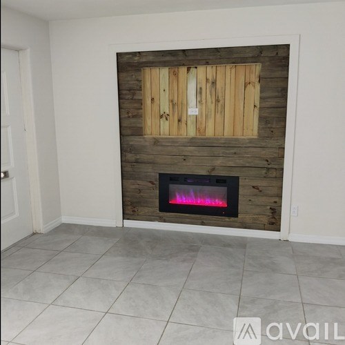 A wood-paneled fireplace with a lit fire inside.