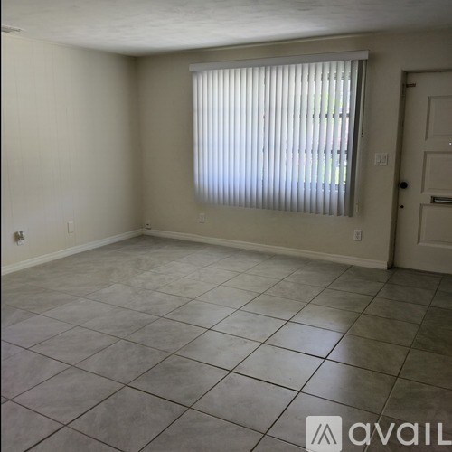 A room with tiled flooring and a window with blinds.