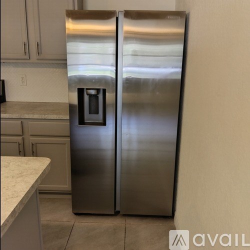 A stainless steel refrigerator with a water dispenser in the middle of the door.