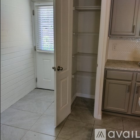 A white door is open to a kitchen with white cabinets.