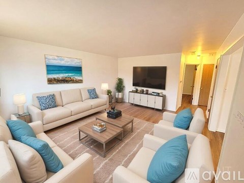 A living room with a white couch, a coffee table, and a painting of a beach scene on the wall.