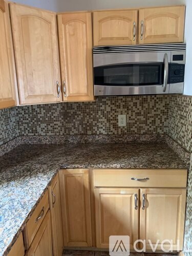 A kitchen with wooden cabinets and a granite countertop.