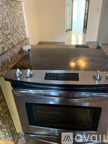 A modern kitchen with a stove top oven and a digital display.