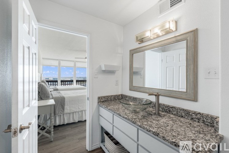 A bedroom with a large mirror and a bed with a view of the water.