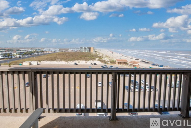 A balcony overlooks a beach and a parking lot.