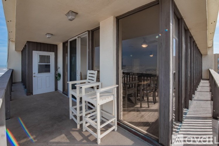 A balcony with a white chair and a glass table.