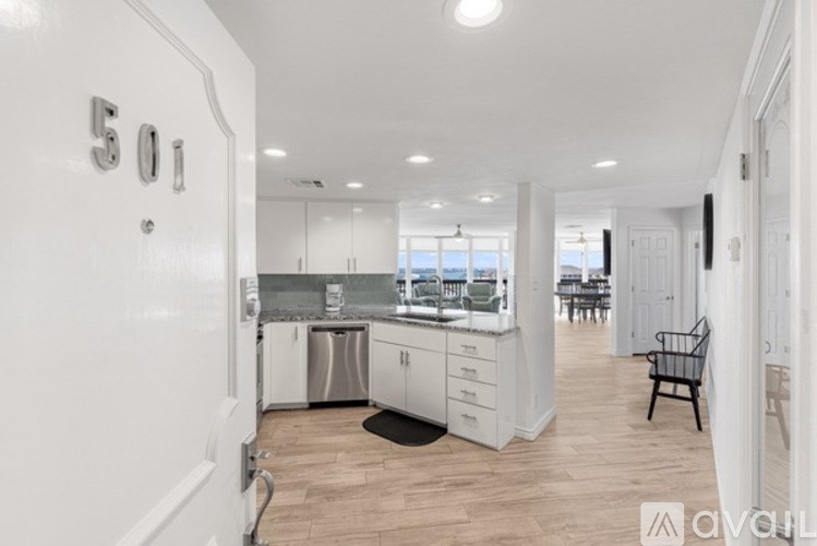 A kitchen with white cabinets and a black chair is visible.