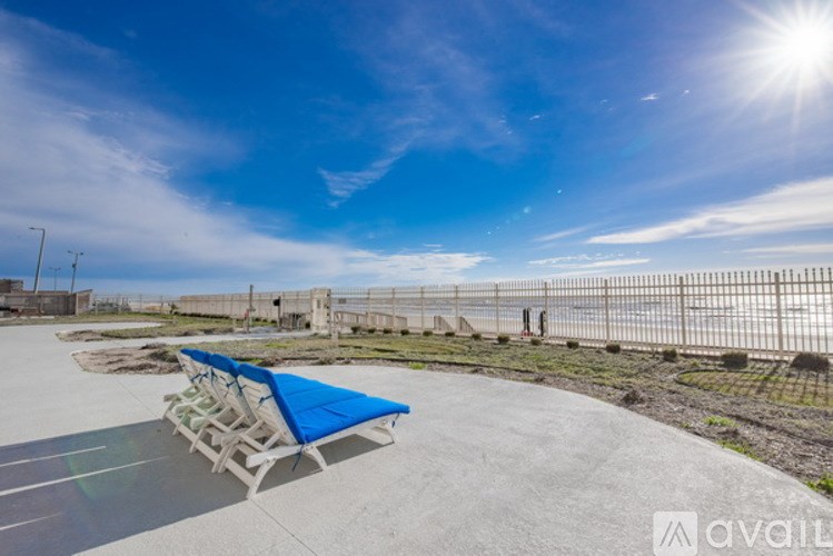 A sunny day at the beach with a blue umbrella and chairs.