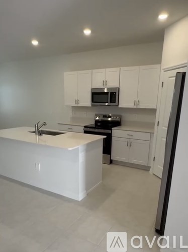 A kitchen with white cabinets and a white island.