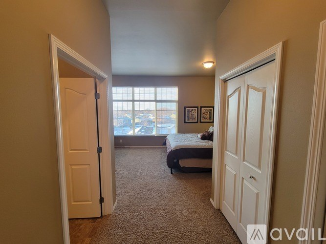 A bedroom with a bed, a window, and a carpeted floor.