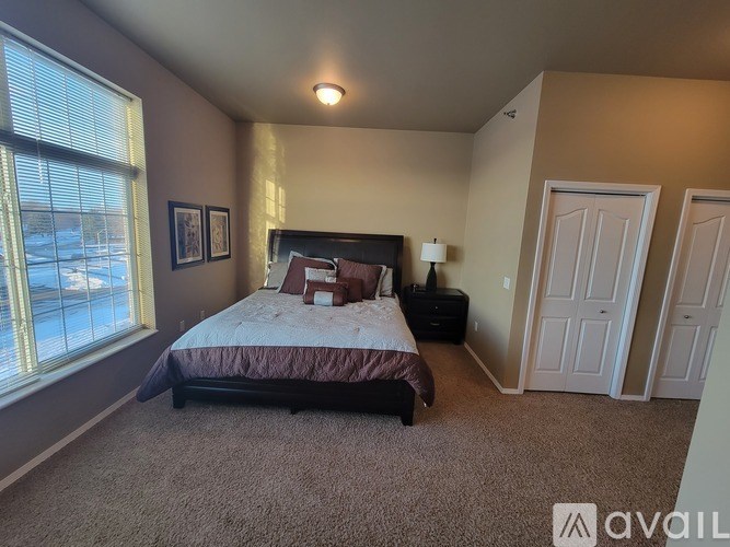 A bedroom with a bed, nightstand, and two doors.