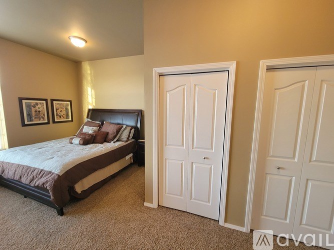 A bedroom with a bed, two doors, and two pictures on the wall.