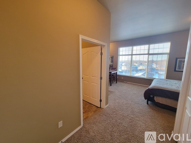 A bedroom with a bed, a chair, and a window overlooking a parking lot.