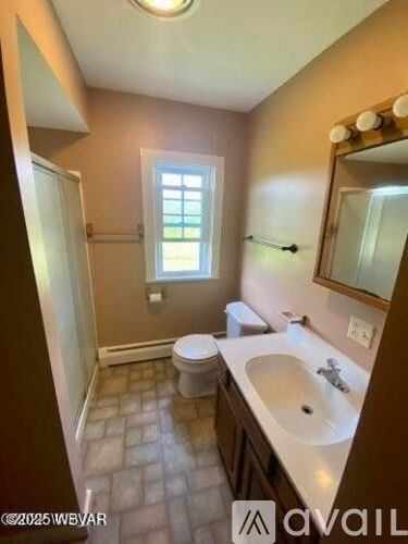 A bathroom with a toilet, sink, and mirror.