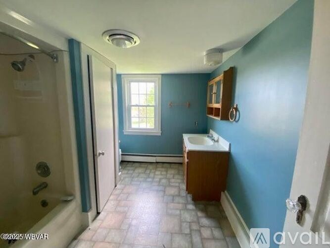 A bathroom with blue walls and a white bathtub.
