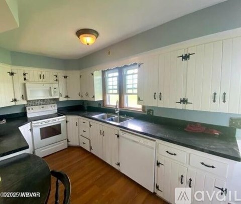 A kitchen with white cabinets and black countertops.