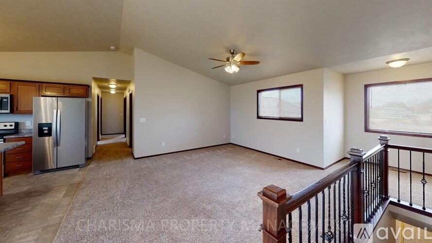 A spacious living room with a stainless steel refrigerator and a ceiling fan.
