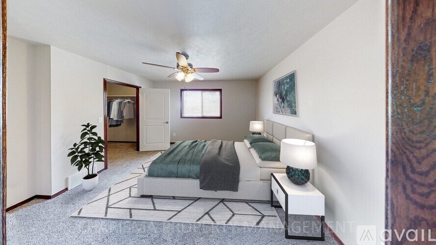 A bedroom with a bed, a couch, and a ceiling fan.