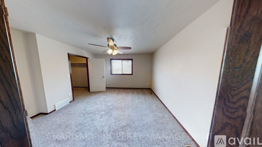 A room with a carpeted floor, a ceiling fan, and a window with blinds.