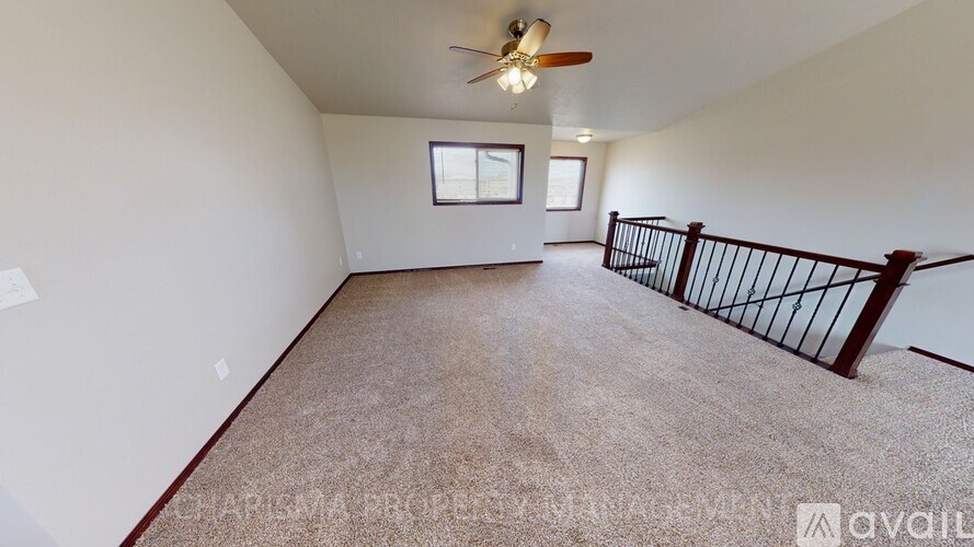 A spacious room with a ceiling fan and carpeted floor.