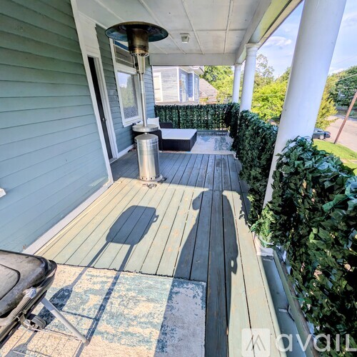 A porch with a wooden floor and a metal pole.